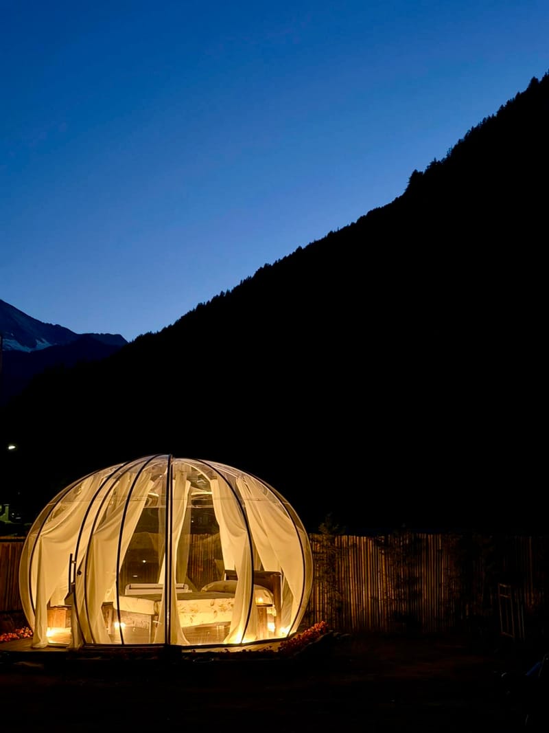 Bolla glamping illuminata di notte tra le montagne