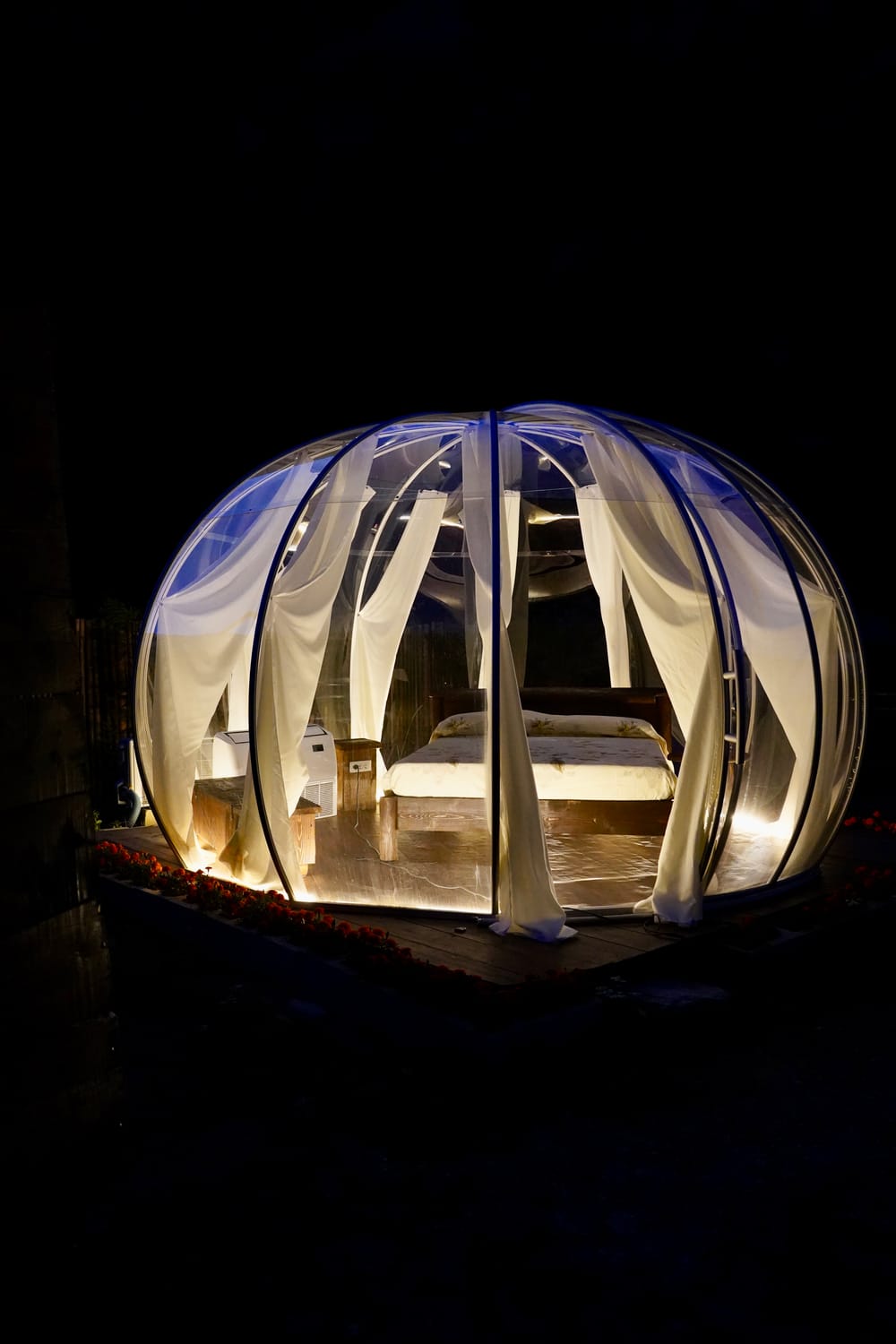Interno di una bolla glamping con letto matrimoniale illuminato di notte