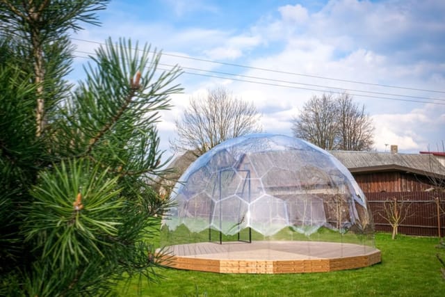 Cupola trasparente su pedana in legno in un giardino a primavera