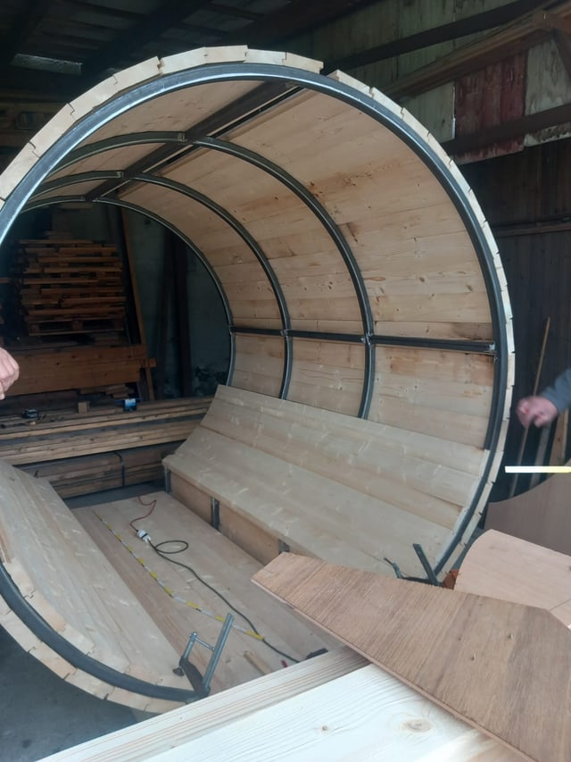 Sauna a botte in costruzione con cerchiature in acciaio e panca già montata