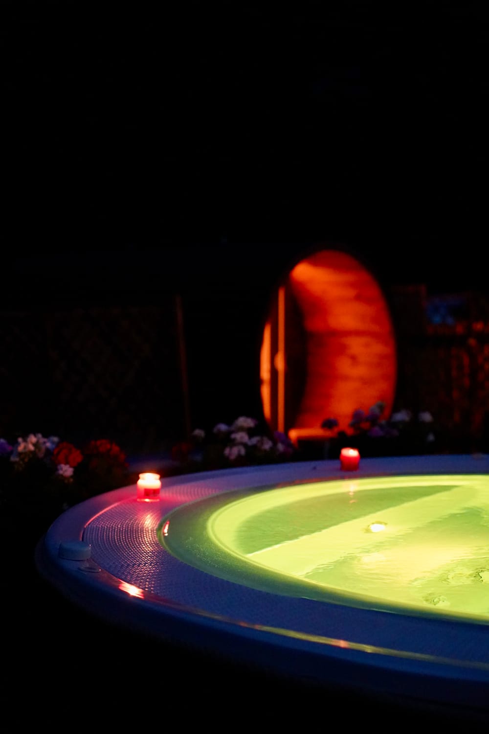 Vasca idromassaggio illuminata di notte con sauna a botte